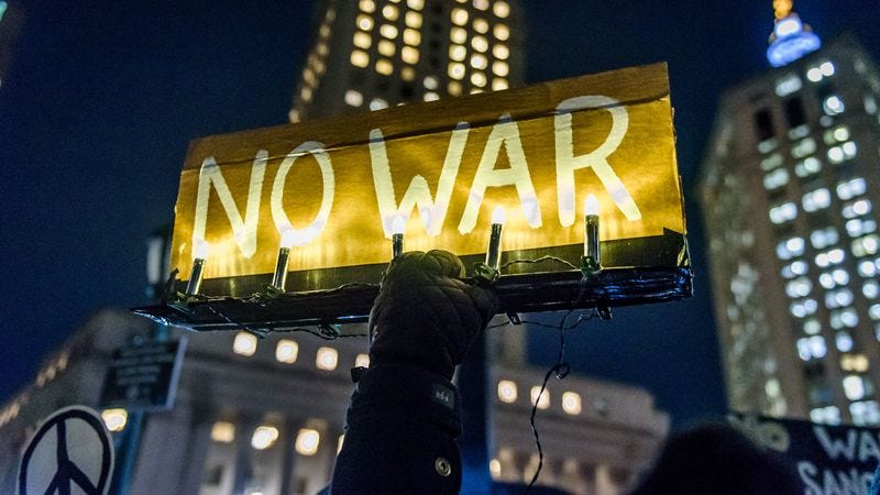 Participant holding an illuminated sign reading NO WAR at