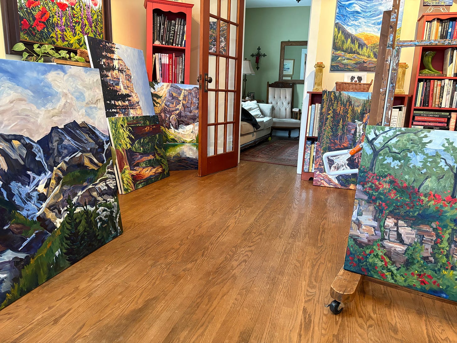 a photo of Caprice's studio with oil paintings stacked on the floor and some hanging on the wall.