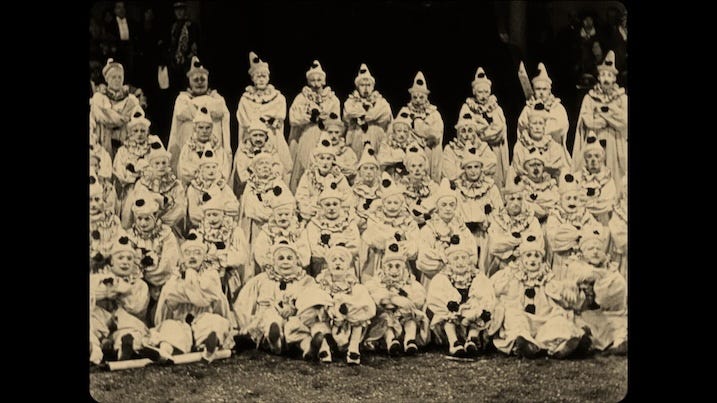 Group of clowns: Large group of clowns seated in formation during a circus sequence in He Who Gets Slapped (1924).