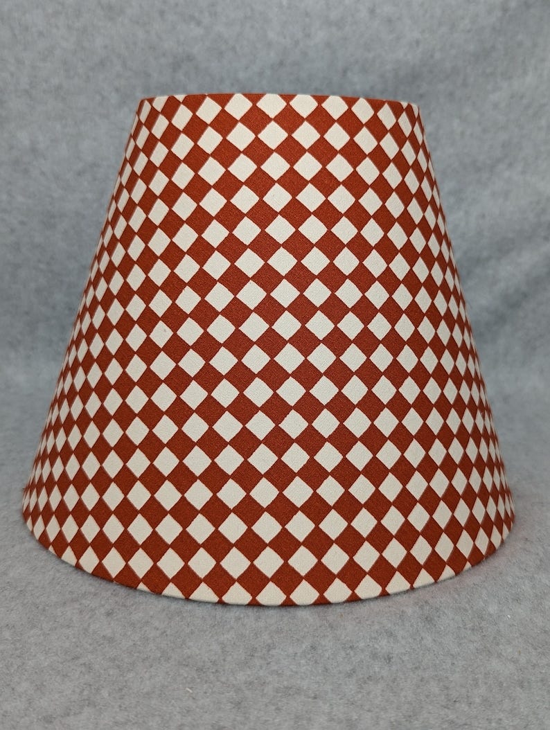 May include: A lampshade with a white background and a red diamond pattern.
