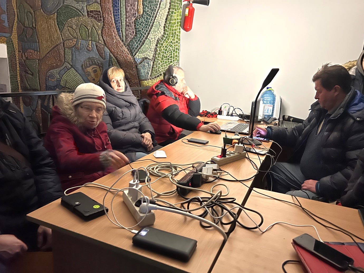 A group of people sitting around a table with computers

Description automatically generated with medium confidence