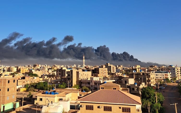 A city with smoke rising from semi high-rise buildings.