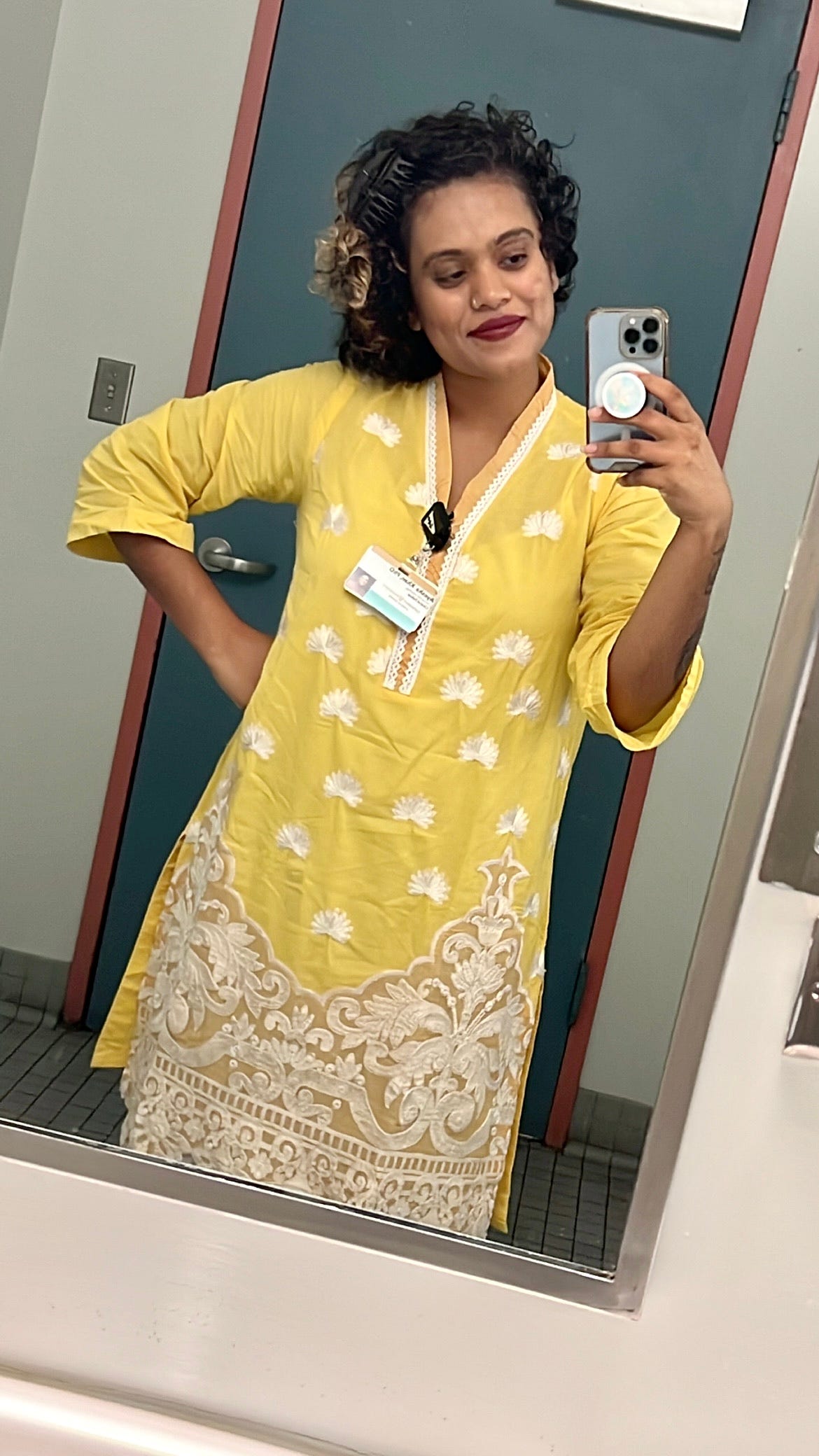 Ayesha taking a selfie in a bathroom mirror at work wearing a handmade, vibrant, yellow, traditional South Asian Shalwar Kameez outfit Ayesha taking a selfie in a bathroom mirror at work wearing a handmade, vibrant, yellow, traditional South Asian Shalwar Kameez outfit