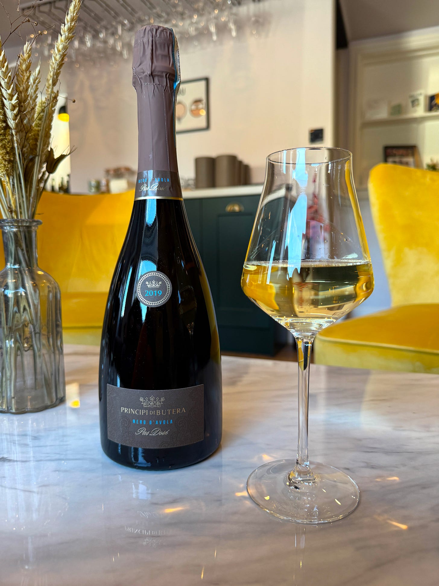a bottle of sparkling nero d'avola wine next to a glass of sparkling wine