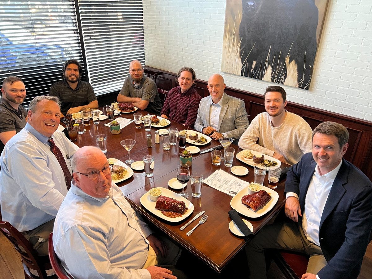 A group of men sitting around a table eating food

Description automatically generated with medium confidence
