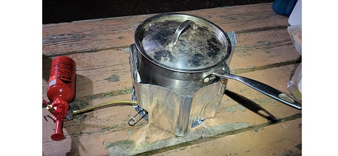 A three-photo sequence: sausages and peppers cooking over an open fire, a lidded pot simmering on a Whisperlite camp stove, and a box of fresh pastries from the iconic Silver Islet General Store.