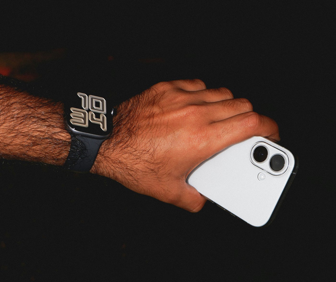 A man’s hand is holding a cellphone and has a smartwatch on his wrist. A man’s hand is holding a cellphone and has a smartwatch on his wrist.