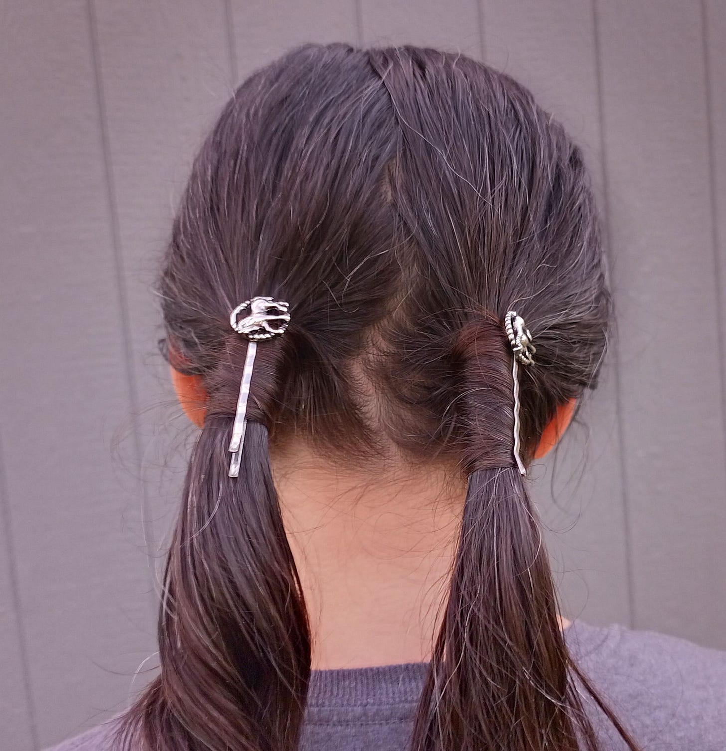 Woman with long brown hair in pigtails with silver horse bobby pins
