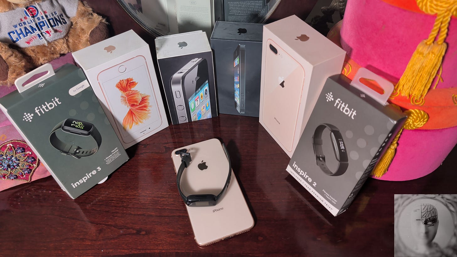 Fitbit and iphone boxes with a black fitbit and rosegold iPhone in front on a vanity, a plush toy Chicago Bear wearing World Cup Champions t-shirt 