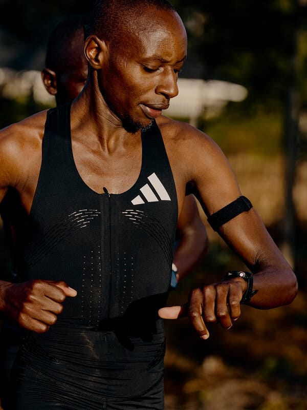 An athlete checks his time. He wears a special running suit black outfit. An athlete checks his time. He wears a special running suit black outfit.