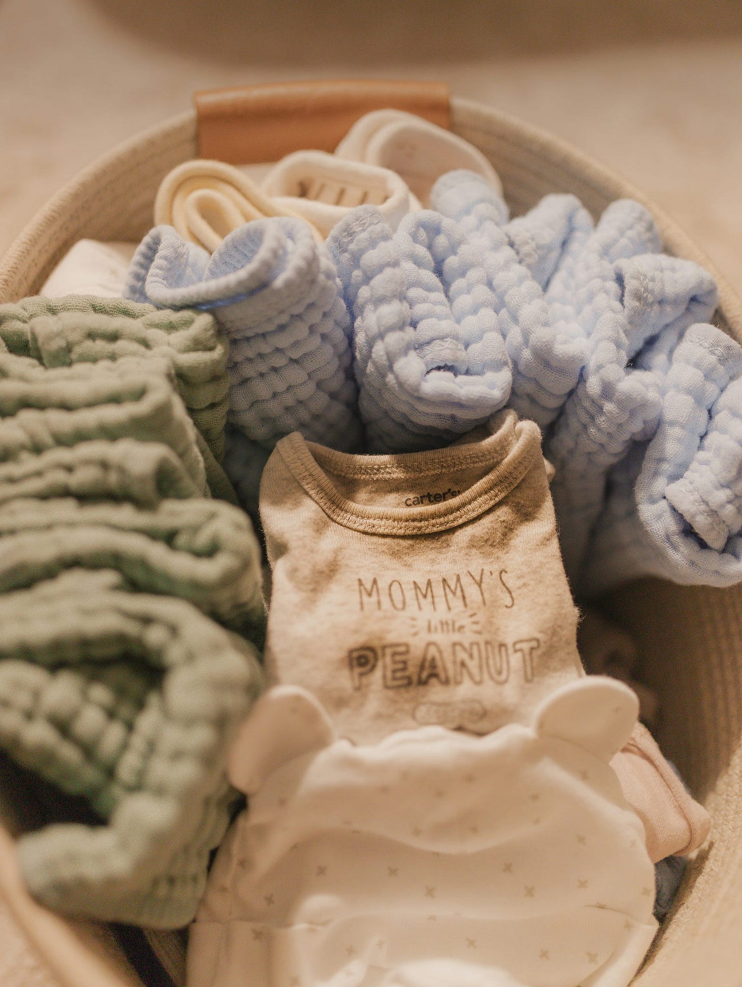 baby clothes in a basket with baby blankets
