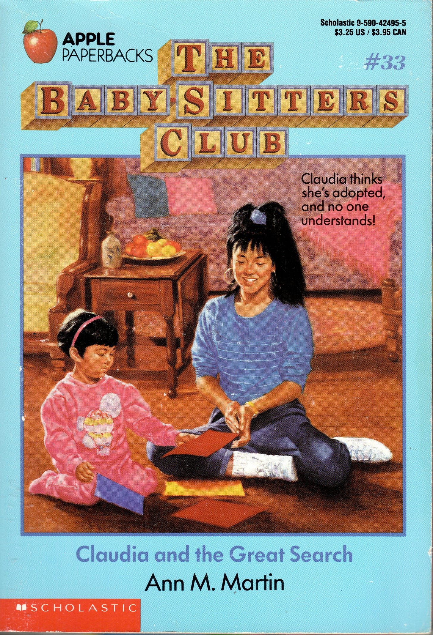 claudia kishi is sitting with emily michelle, a child, with some squares that have colors on the floor