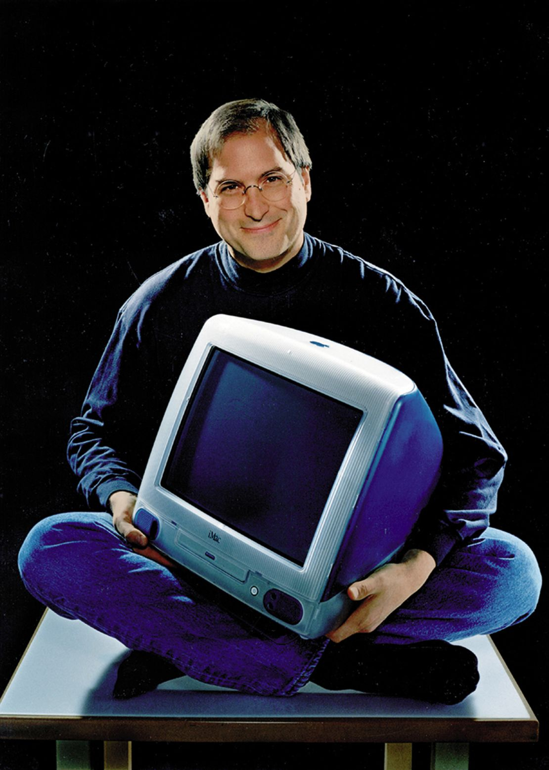Feb. 19, 1999 - Cupertino, California, U.S. - Apple founder and current chief STEVE JOBS, cross legged and smiling as he holds the iMac that has become the hottest-selling computer on the market. The computer now comes in five fruit-inspired colors including blueberry and strawberry. Shown is the original Bondi Blue color. Feb. 19, 1999 - Cupertino, California, U.S. - Apple founder and current chief STEVE JOBS, cross legged and smiling as he holds the iMac that has become the hottest-selling computer on the market. The computer now comes in five fruit-inspired colors including blueberry and strawberry. Shown is the original Bondi Blue color.