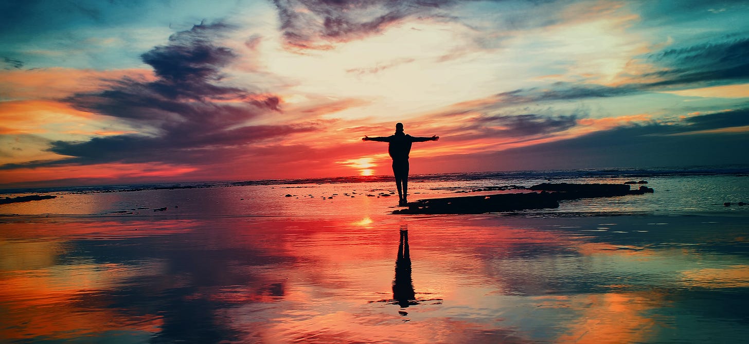 Man on beach sunset holding out arms