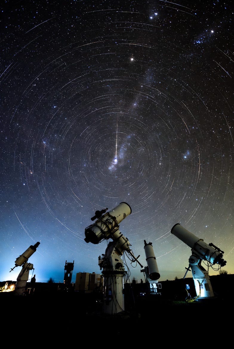 A conceptual photograph of telescopes observing a starry night sky, symbolizing astronomical discovery.