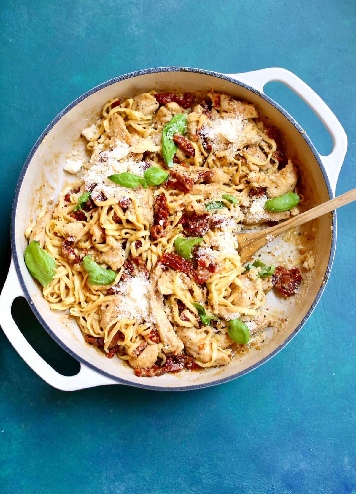 a skillet wth pasta and chicken in it on a blue background.