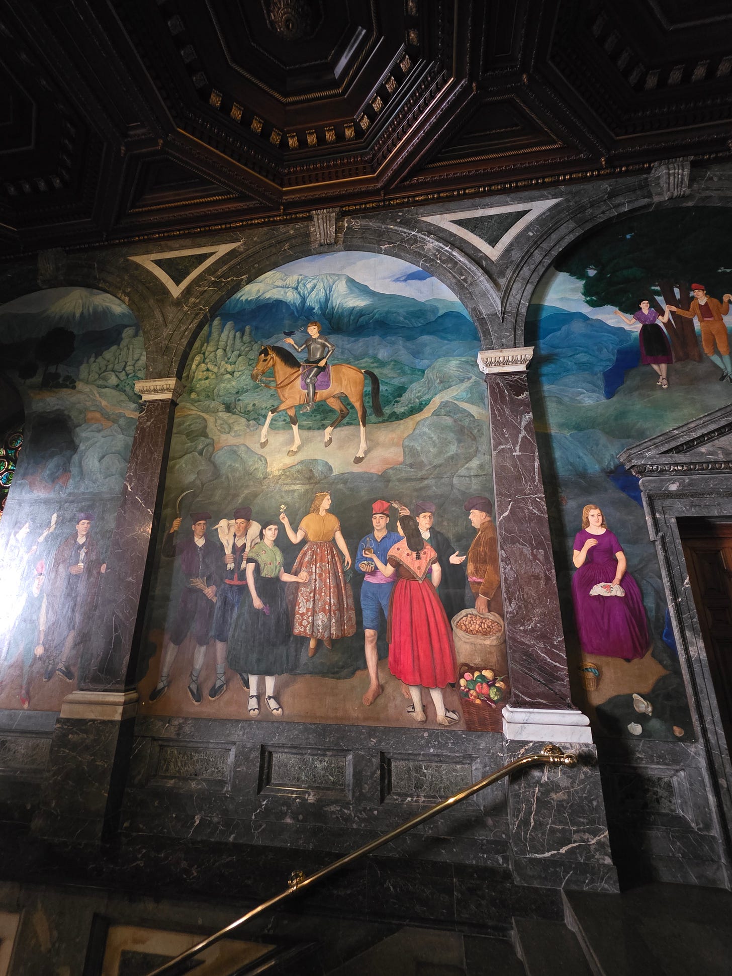 Mural de Miquel Viladrich en la parte superior delas Escaleras Negras en el Ayuntamiento de Barcelona. Vemos un grupo de personas con vestidos tradicionales de Cataluña.