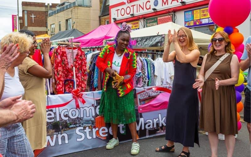 May be an image of 5 people, crowd and text that says "Ii+ t TOOTING 0 M MT TOOTING TOTT STREET TREE TOOTING INU TOO elcome Mark vn Stre t t"