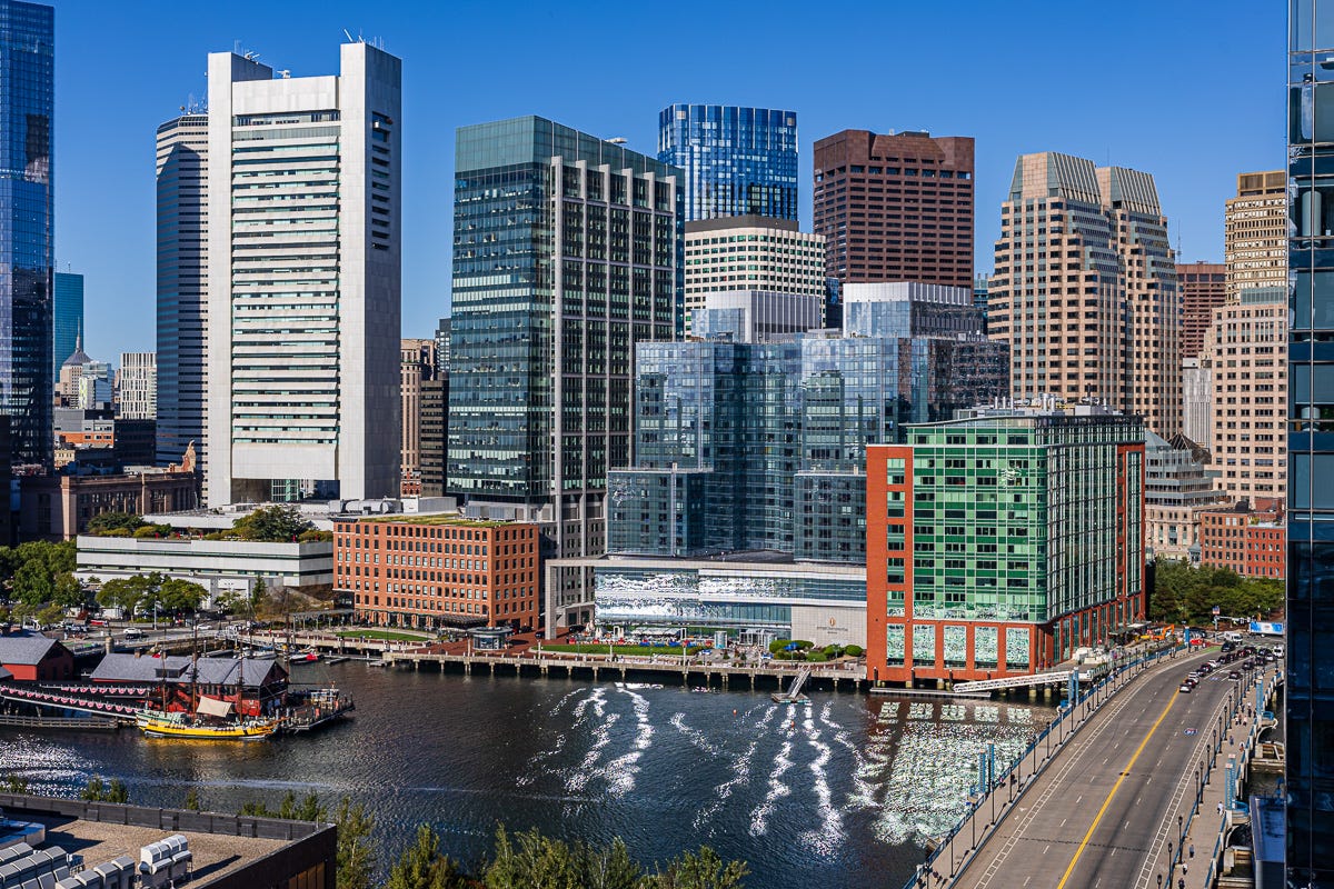 Morning Boston skyline with twisting light reflections across channel.