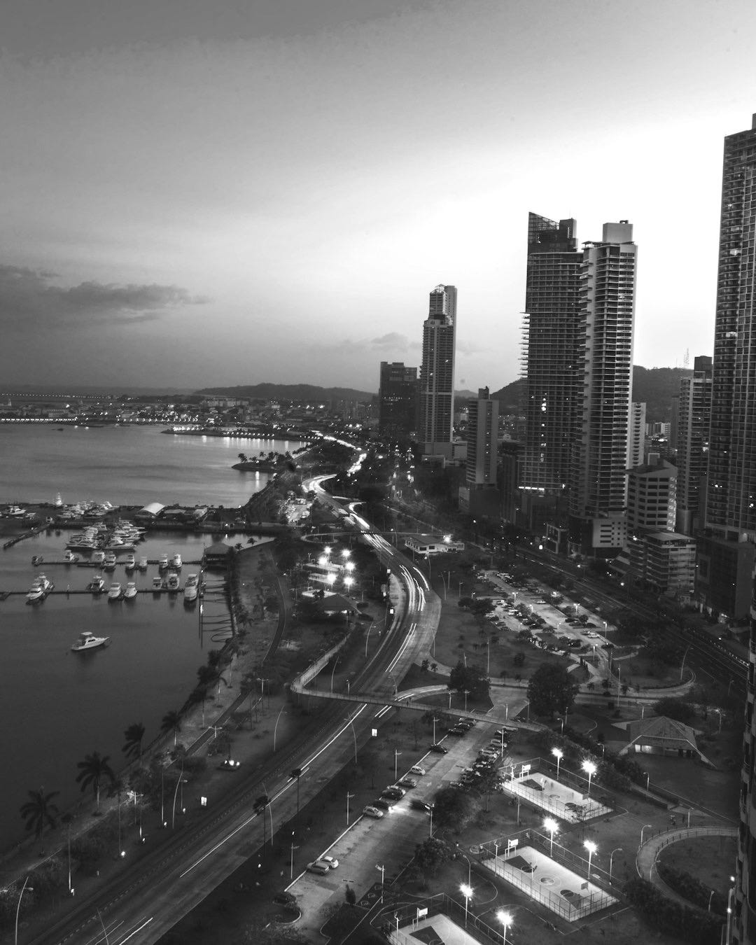 high rise buildings near body of water in distant of mountain