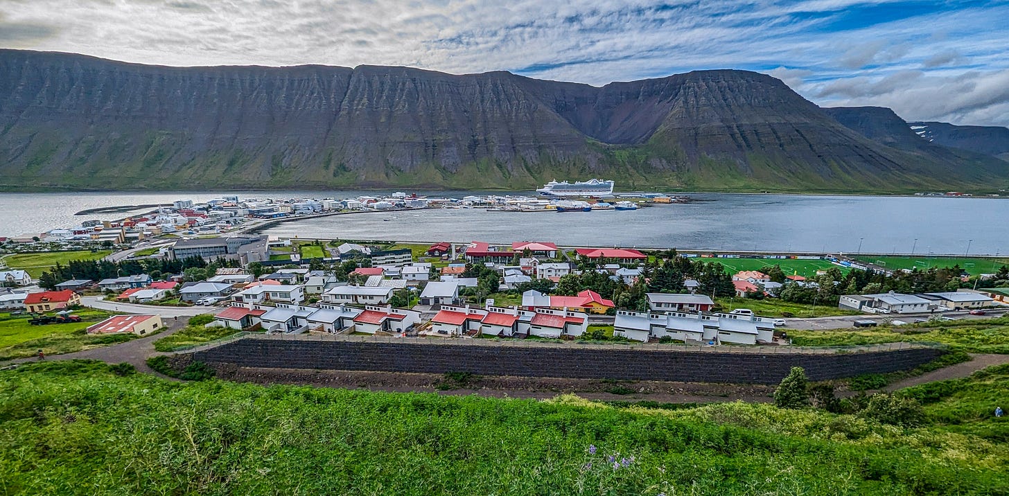 Wide angle shot showing the town located on a flat piece of land along the fjord, dramatic mountains rising in the background. Wide angle shot showing the town located on a flat piece of land along the fjord, dramatic mountains rising in the background.