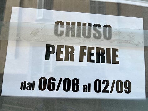 Chiuso per ferie, handwritten signs saying the shops are closed for the month of August and overgrown plants on the sidewalk