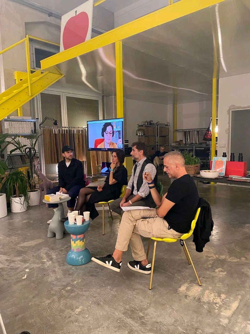 Gianvito Fanelli, Valentina Di Michele, Andrea Fiacchi e Antonio Grillo parlano di Scrivi e lascia vivere nello spazio LOI di Conversano, una design boutique molto cool e arredata sui toni del giallo. Dietro di loro, su un maxischermo, ci sono io collegata dalla Catalogna.