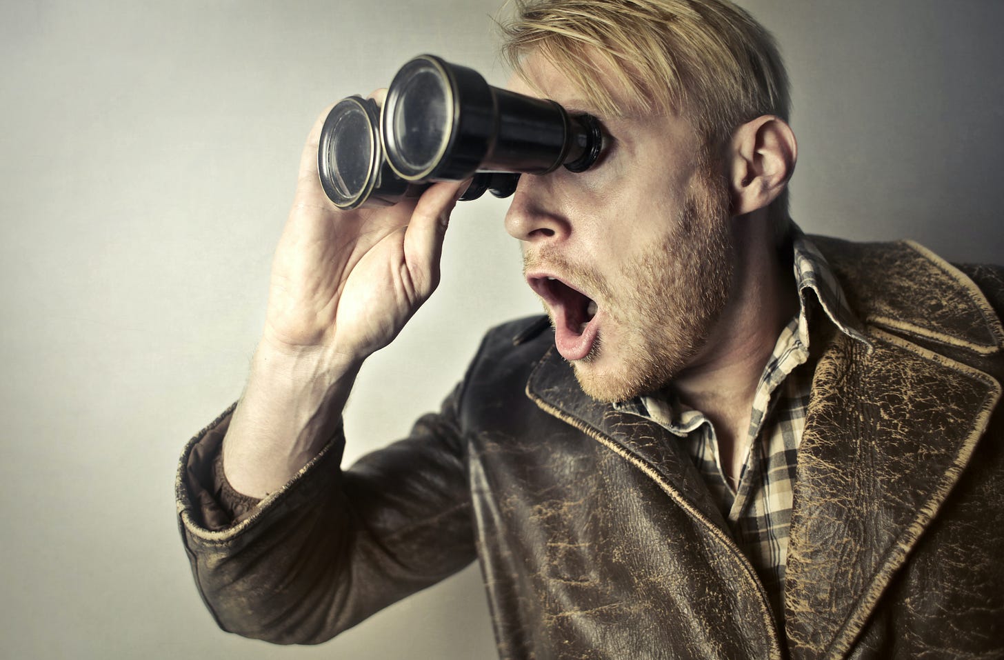 Man looking from binoculars with a shocked expression Man looking from binoculars with a shocked expression