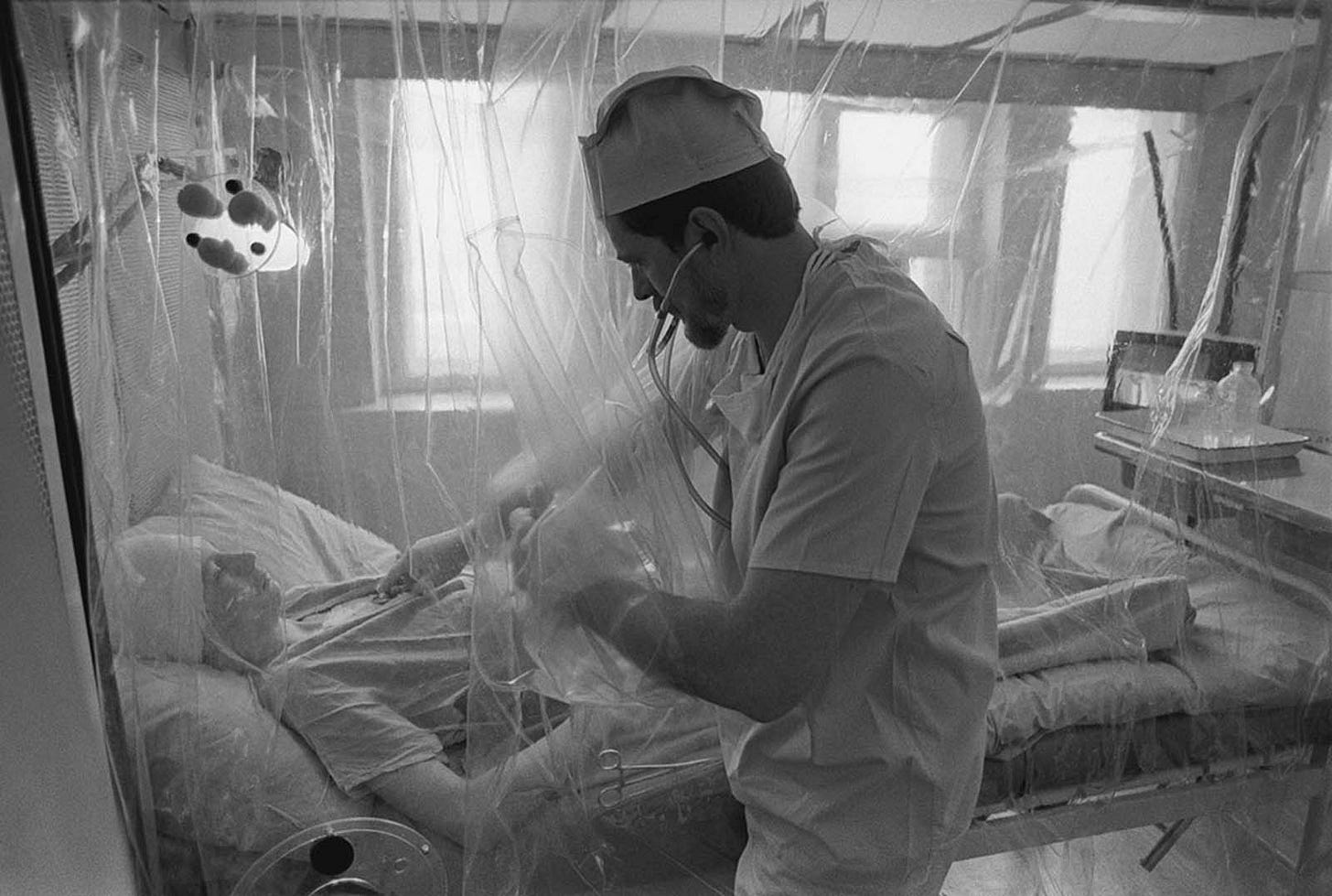At Moscow’s No. 6 radiation clinic, a patient recovers from a bone-marrow operation, examined by a doctor through a sterile, isolated chamber to prevent contamination.