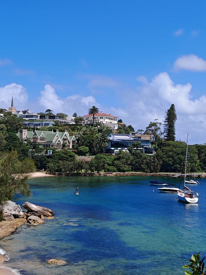 1. A view of a cove with houses around it and boats in the water. 2. An ibis lingering by a blonde man eating a sandwich. 3. The multi-layered strawberry watermelon ice cream. 4. A man looking humorously scared in front of the Luna Park entrance, depicting a giant grinning face.