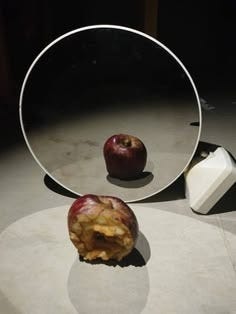 This may contain: an apple sitting in front of a mirror on the floor next to it's reflection This may contain: an apple sitting in front of a mirror on the floor next to it's reflection