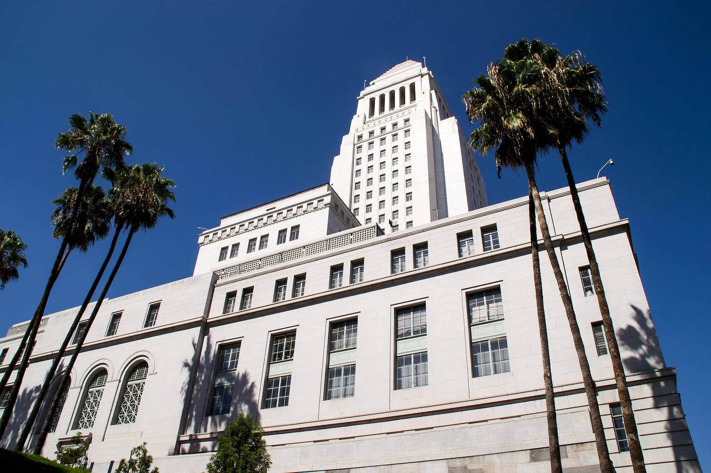 The exterior of Los Angeles City Hall surrounded by palm trees on a sunny day