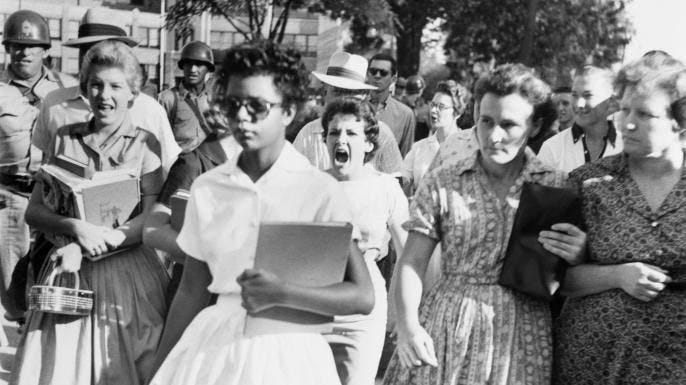 An alternate-angle view of Elizabeth Eckford on her first day of school, taken by an Associated Press photographer. Hazel Bryan can be seen behind her in the crowd.