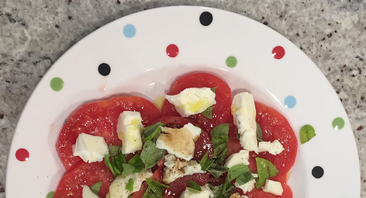 Tomatoes, mozzrella, basil, and olive oil on a polka-dotted plate.