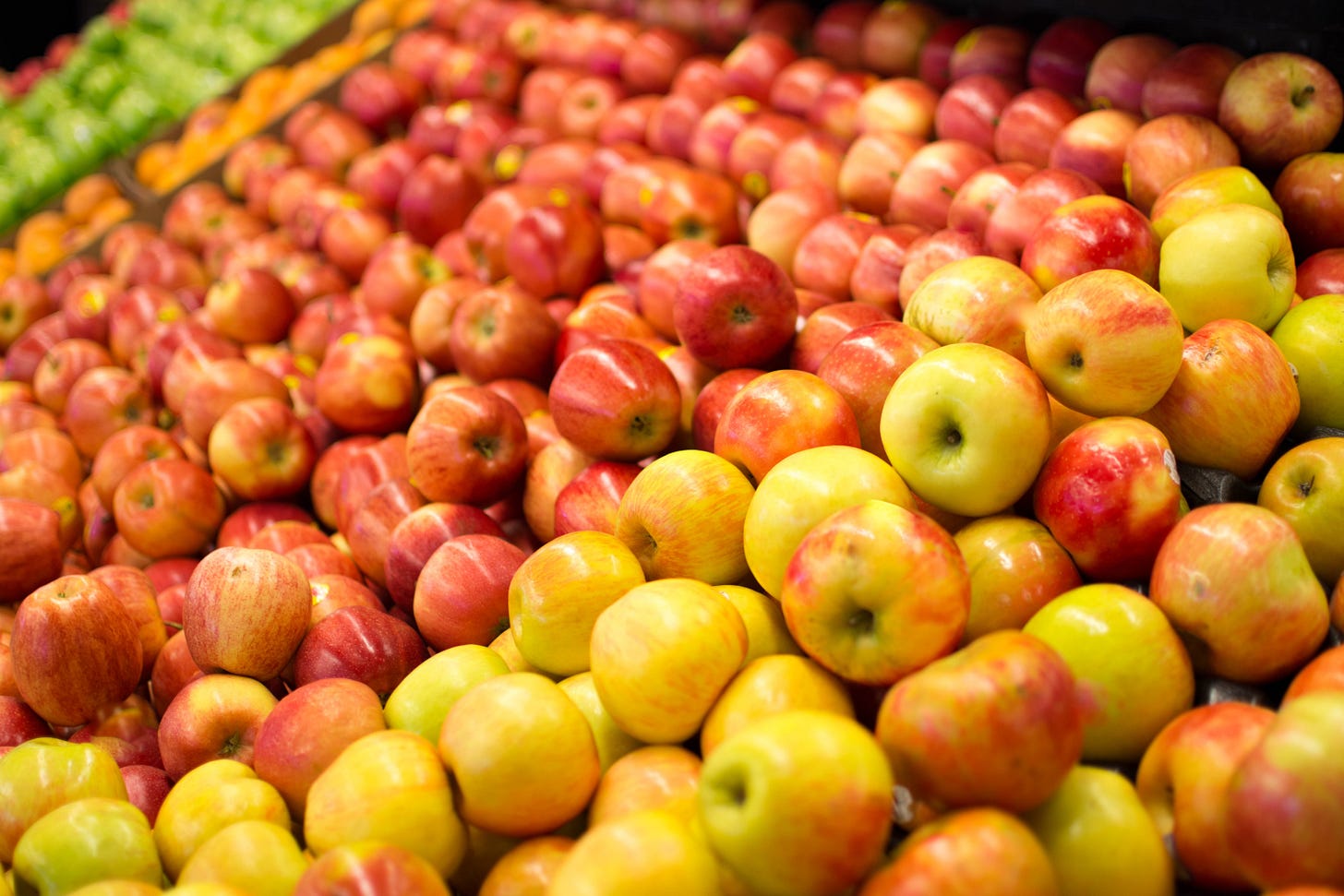 A color photo of different apple varieties on display in a market