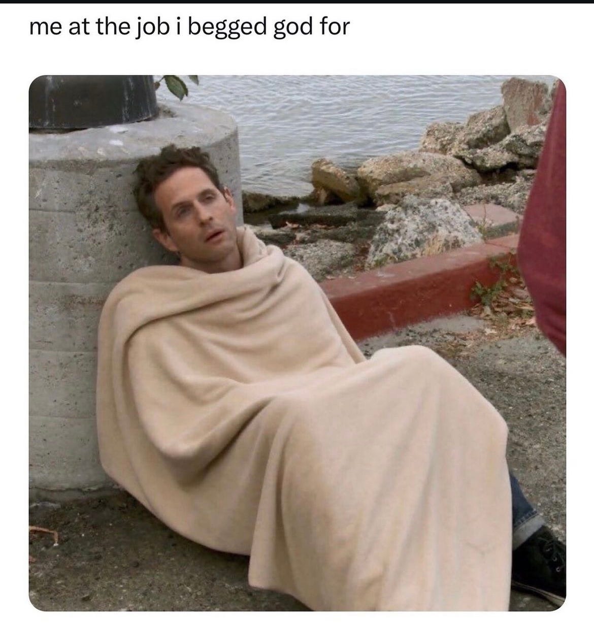 Still from It's Always Sunny showing Dennis Reynolds looking haggard, lying on the ground under a blanket, and the caption says "me at the job I begged god for"