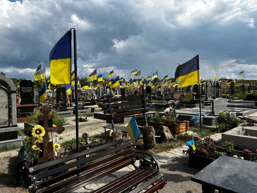 A cemetery with flags and benches

Description automatically generated