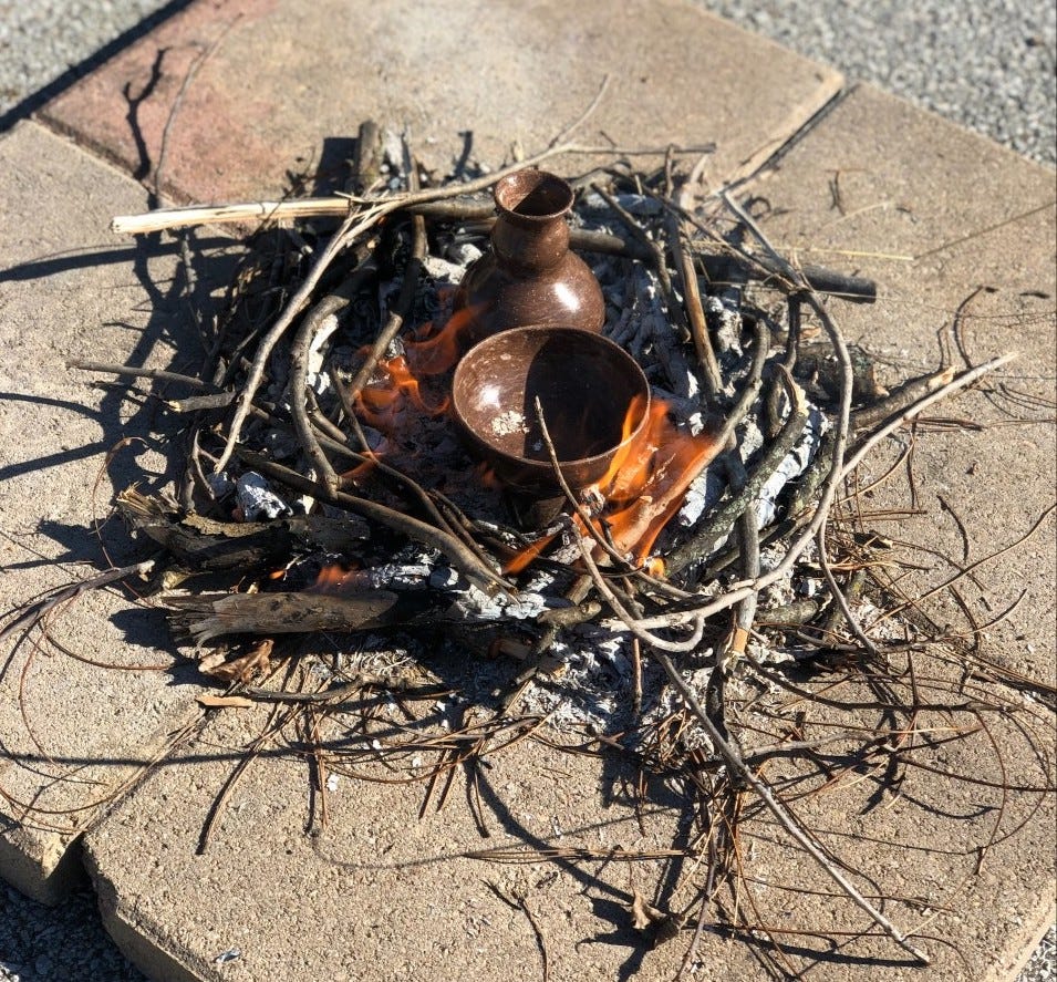 Two brown pots sit in a fire burning on top of stone tiles. Two brown pots sit in a fire burning on top of stone tiles.