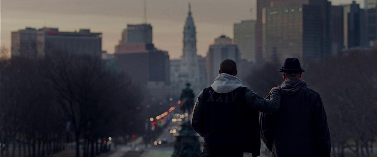 A person standing on a bridge looking at a city

Description automatically generated
