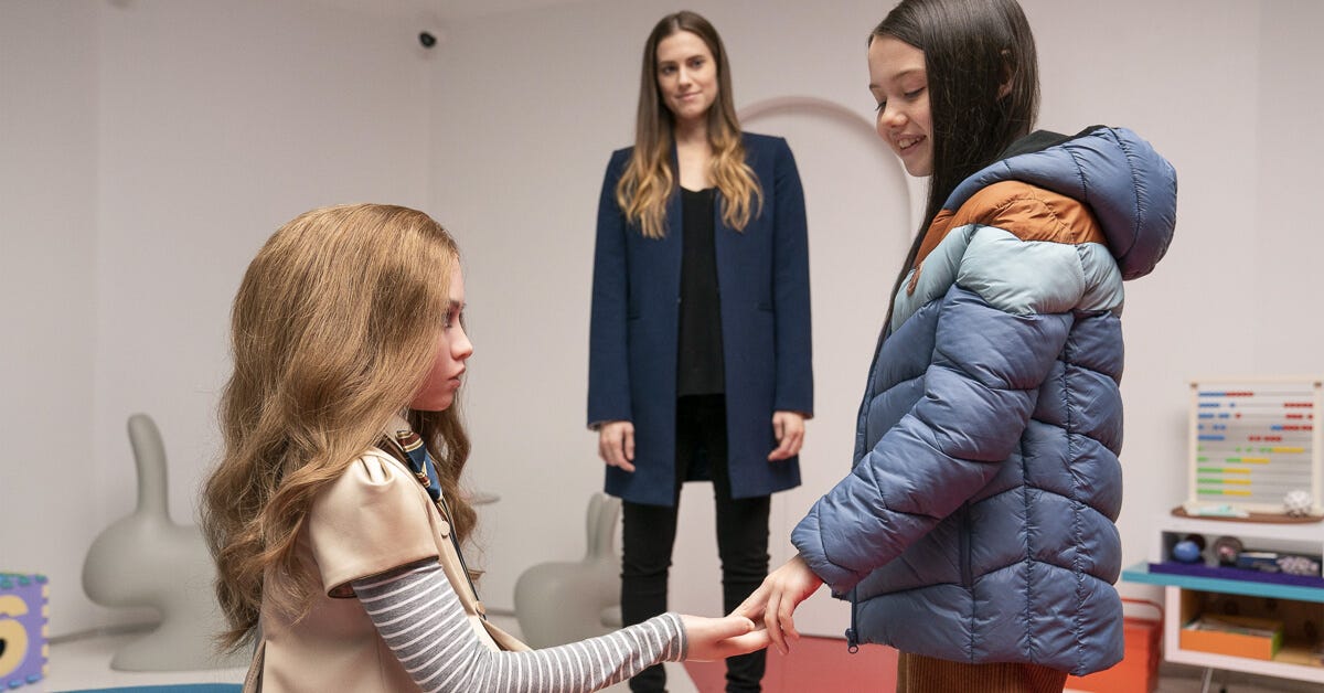 M3GAN holding hands with her new human companion during their introduction, with Allison Williams watching in the background. M3GAN holding hands with her new human companion during their introduction, with Allison Williams watching in the background.