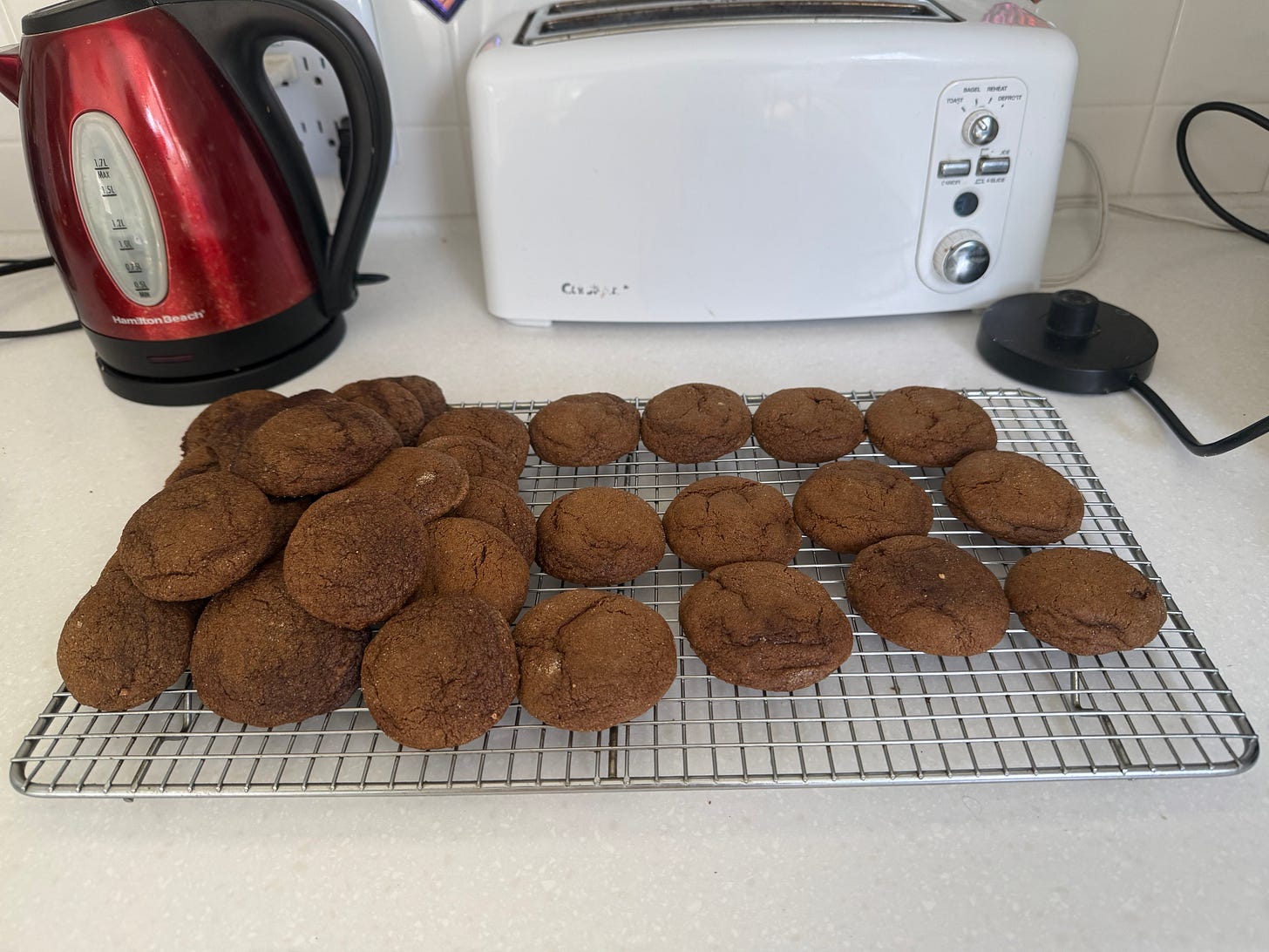 Pile of ginger cookies on a colling rack on a kitchen counter.