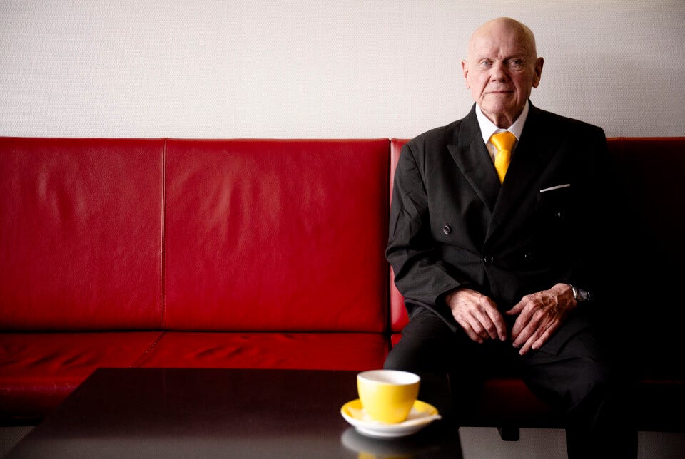 A man who calls himself "cliff from las vegas" sits on a red sofa.