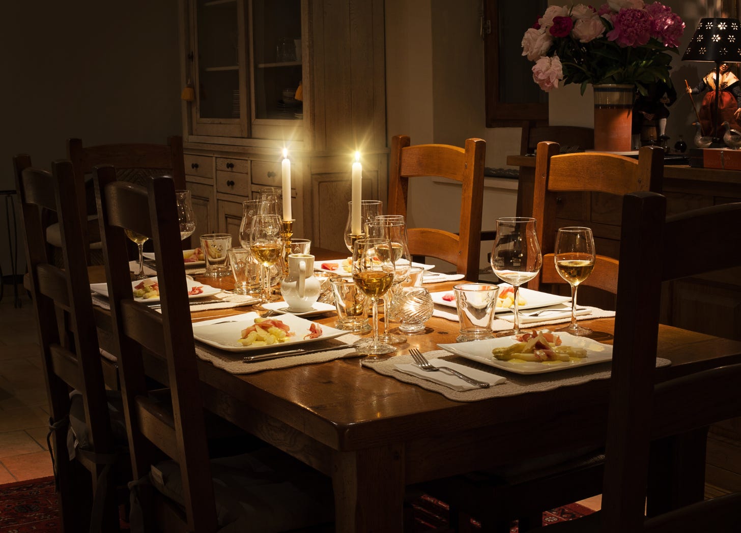 A warmly lit dinner table set for a shared meal, with glowing candles, wine glasses, and plates of food, evoking connection, tradition, and family gathering.