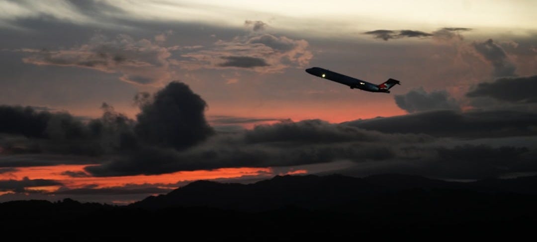 a plane flying through a cloudy sky at sunset