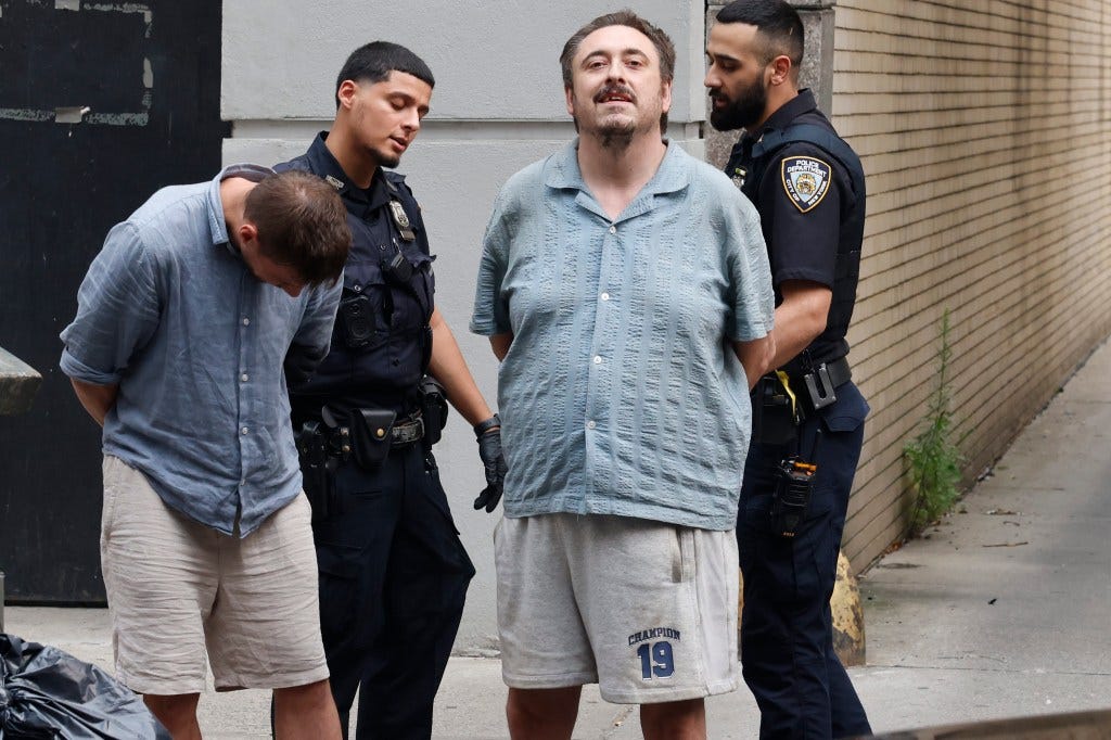 Andrew Truelove, an alleged suspect, being led away by two police officers with a third person handcuffed in front of him. Andrew Truelove, an alleged suspect, being led away by two police officers with a third person handcuffed in front of him.
