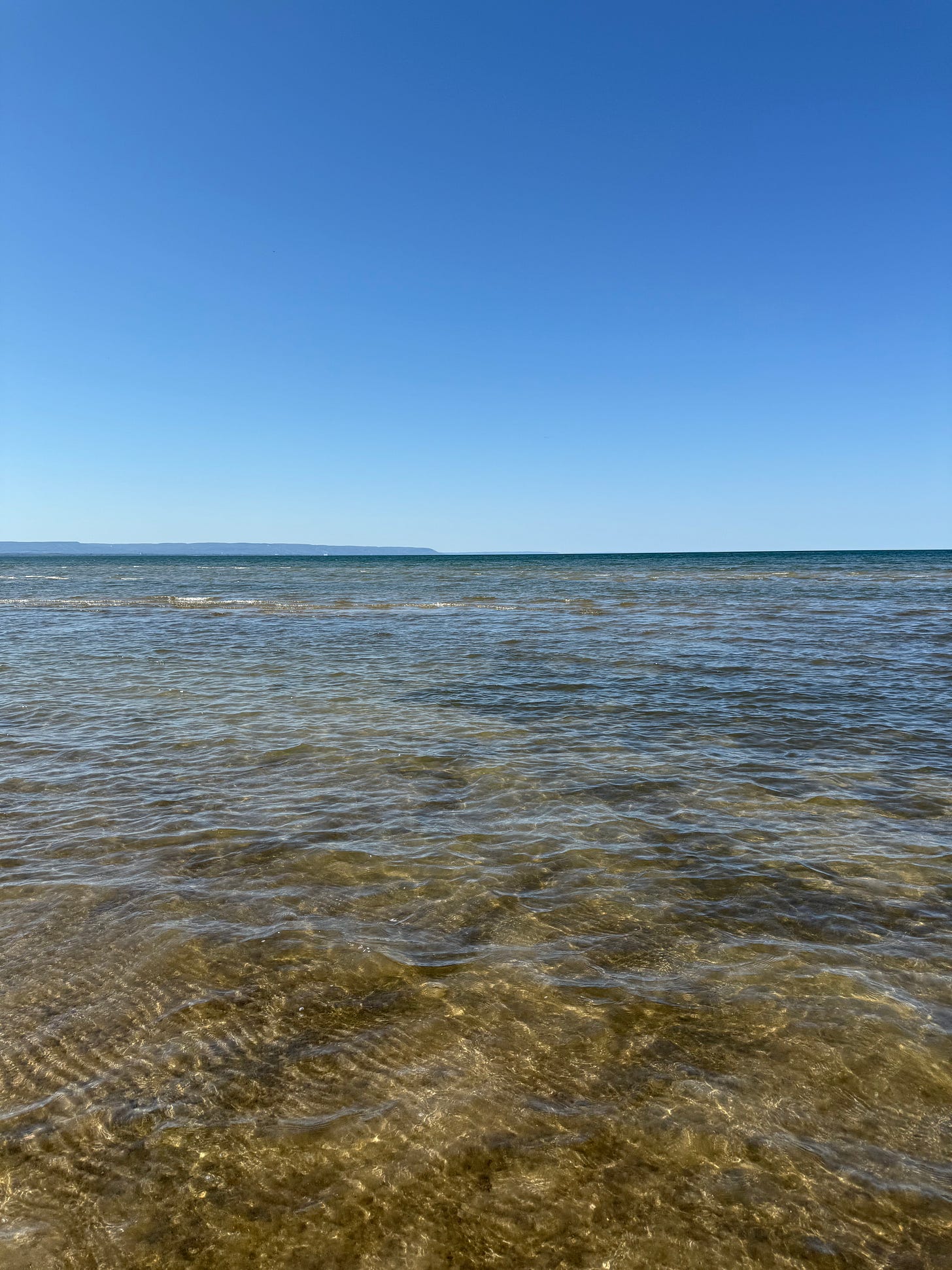 Clear shallow water of Wasaga Beach stretching into the horizon beneath a cloudless blue sky. Clear shallow water of Wasaga Beach stretching into the horizon beneath a cloudless blue sky.