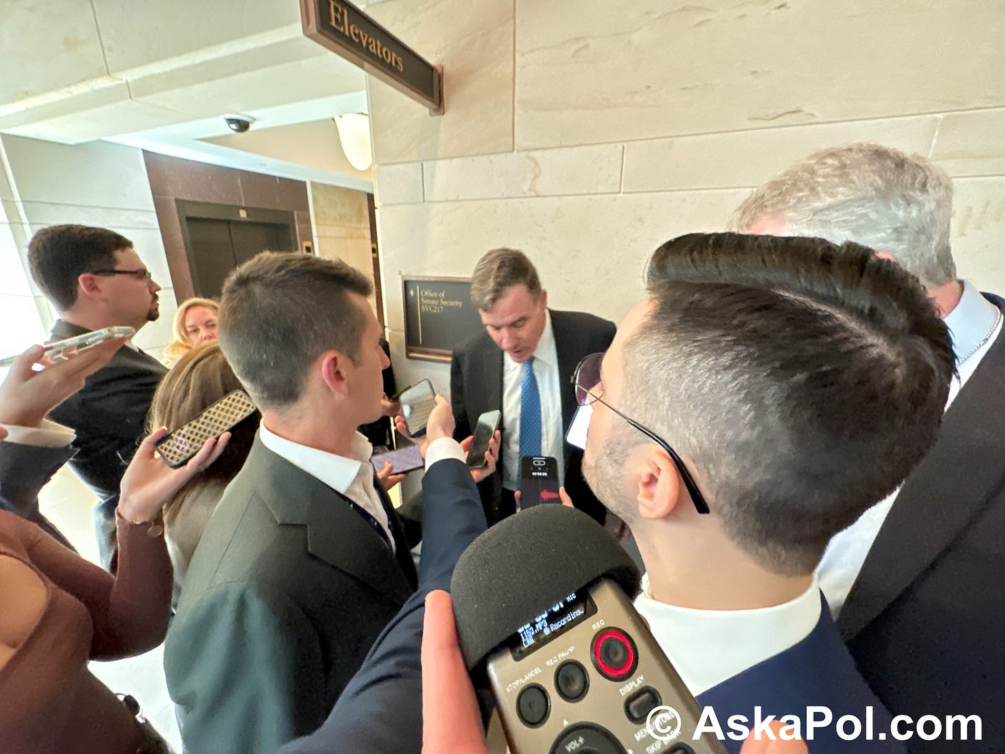 Man in suit answers questions from reporters Photo: Matt Laslo © www.askapoluaps.com 