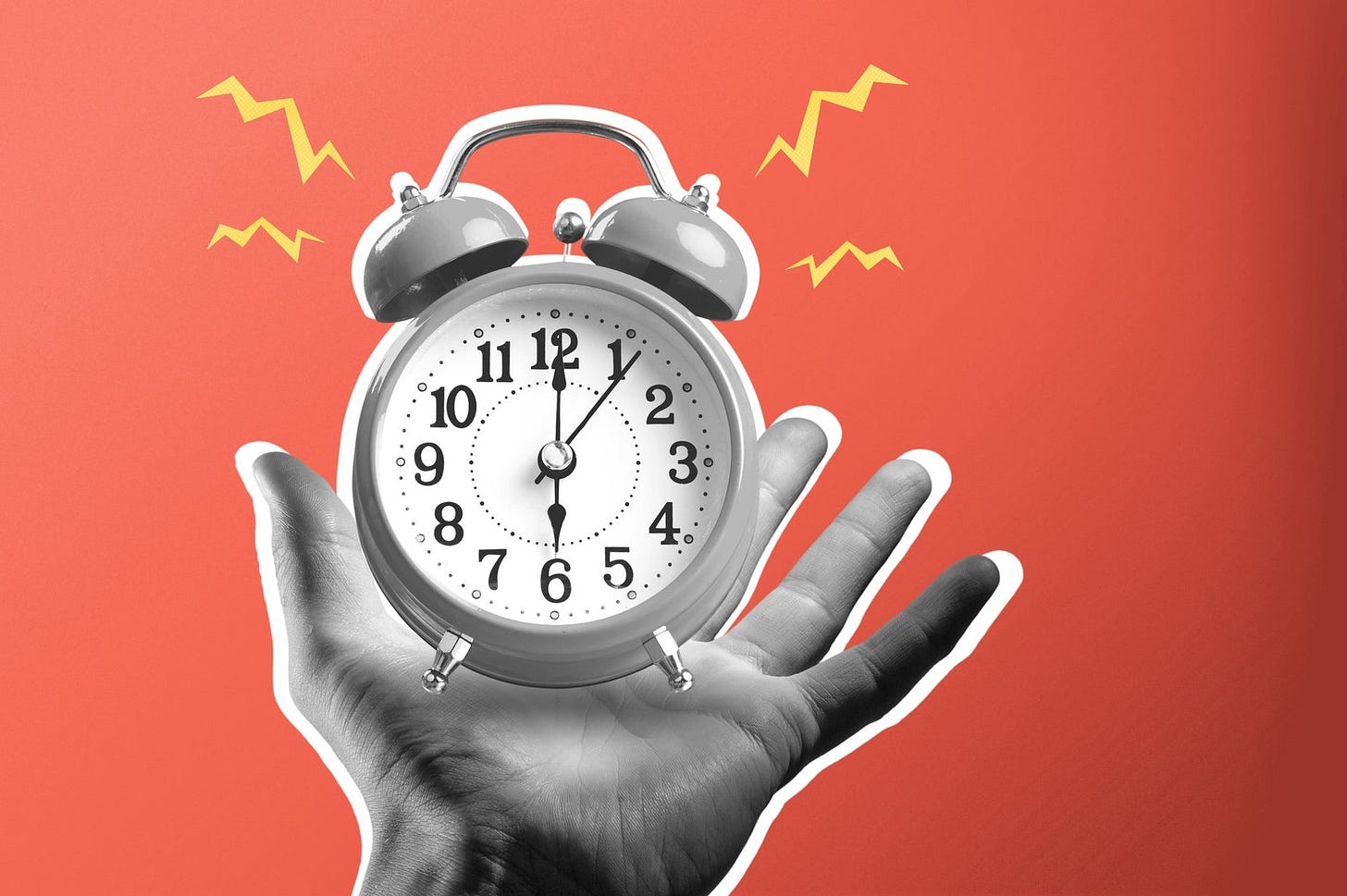 A hand holding a ringing alarm clock
