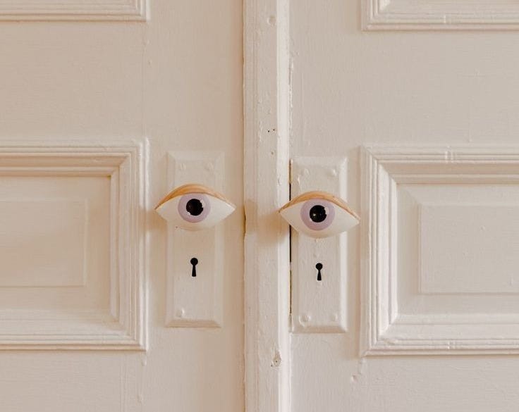 This may contain: two eyeballs are on the front door of a white house with black latches