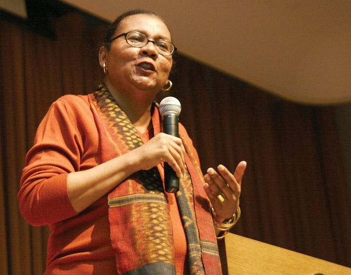 gallery of two photos. On the left is a woman speaking into a microphone. Her hair is pulled back and she is wearing glasses and dressed in orange with a printed scarf. On the right is a man looking into the camera lens. He is wearing a glasses and his clothes have a blue collar and a white collar.